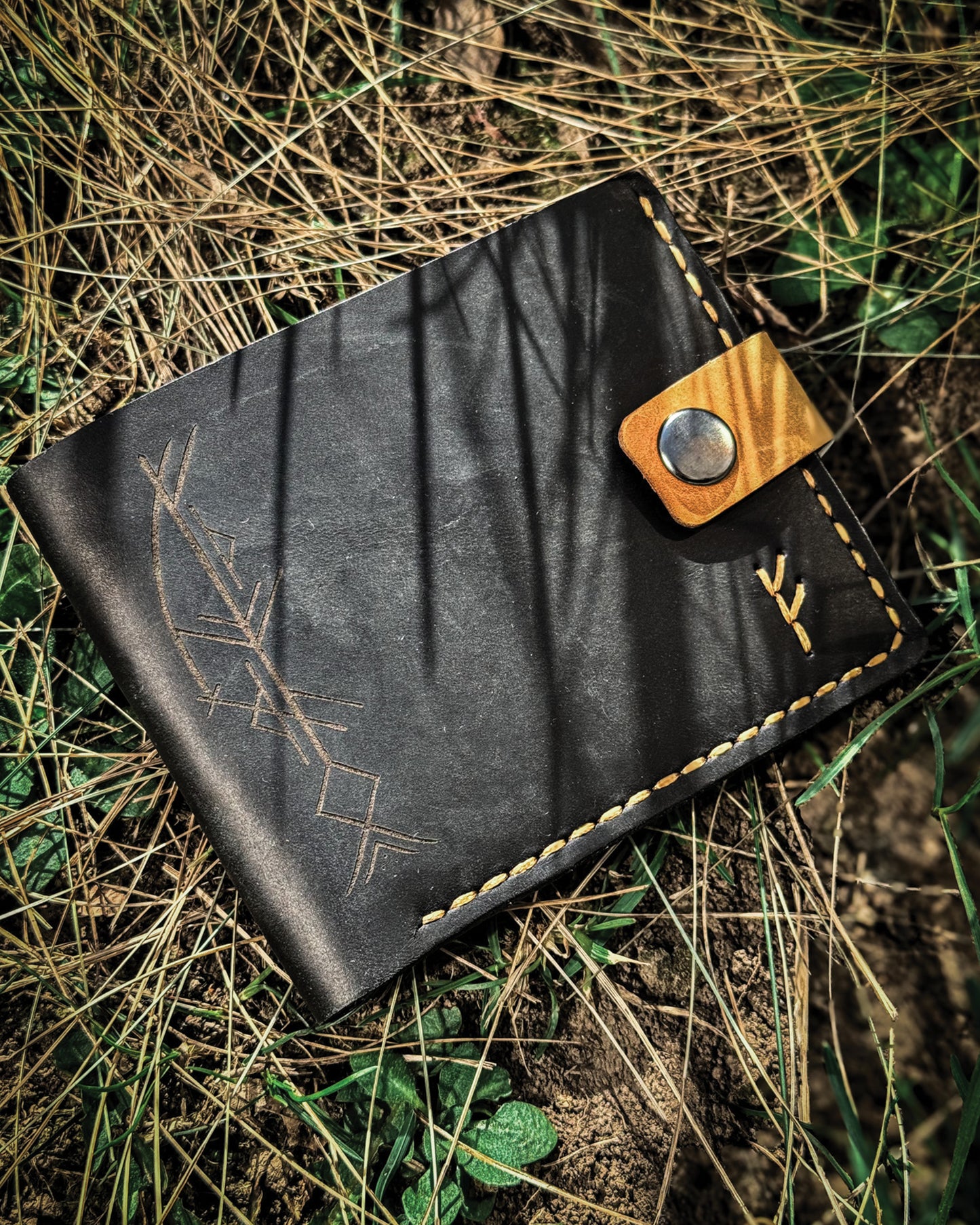 Handmade Viking leather wallets engraved with a custom Bindrune for wealth, prosperity & luck. Features stitched Fehu rune. Available in navy, black & green. Norse mythology meets everyday style.