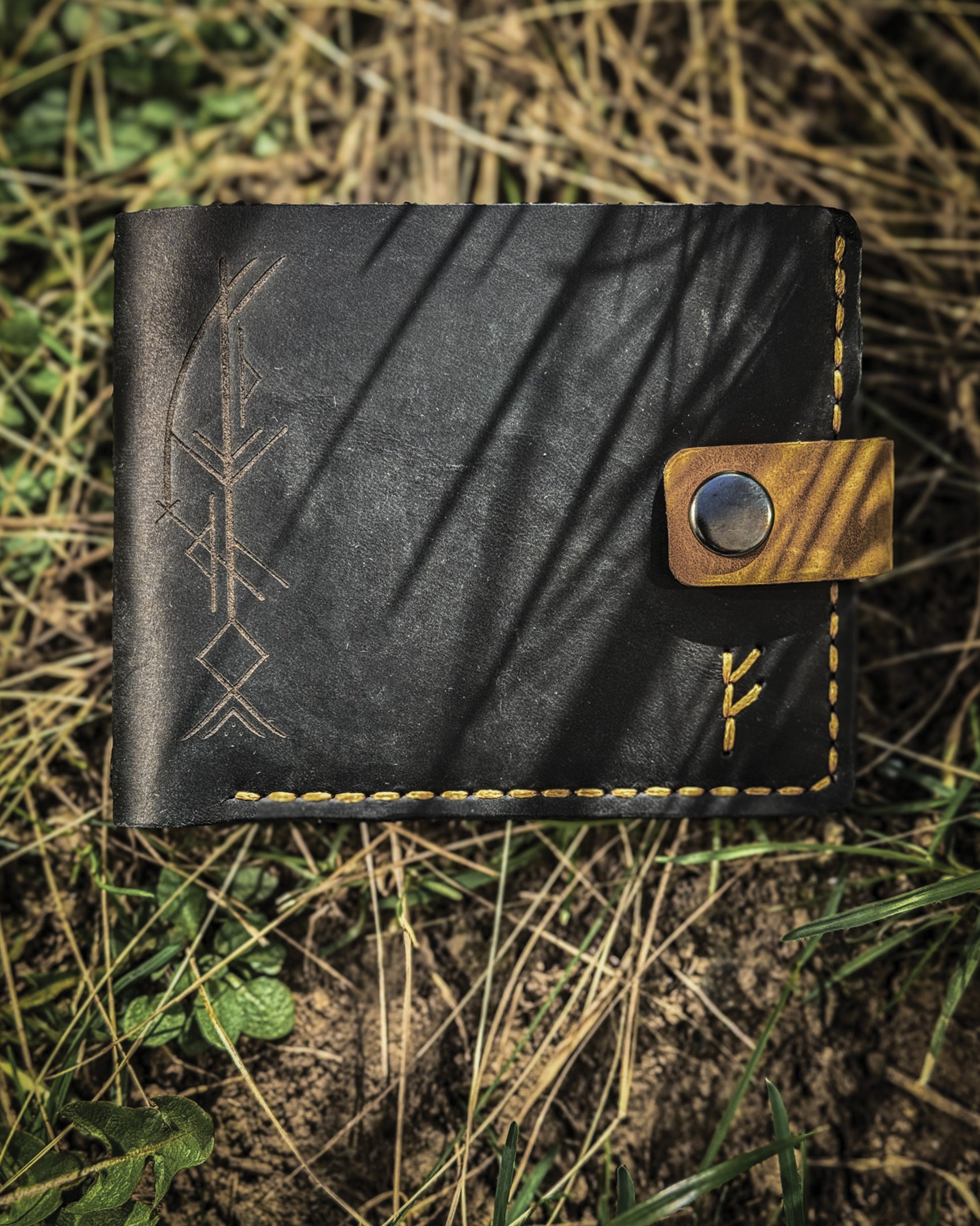 Handmade Viking leather wallets engraved with a custom Bindrune for wealth, prosperity & luck. Features stitched Fehu rune. Available in navy, black & green. Norse mythology meets everyday style.