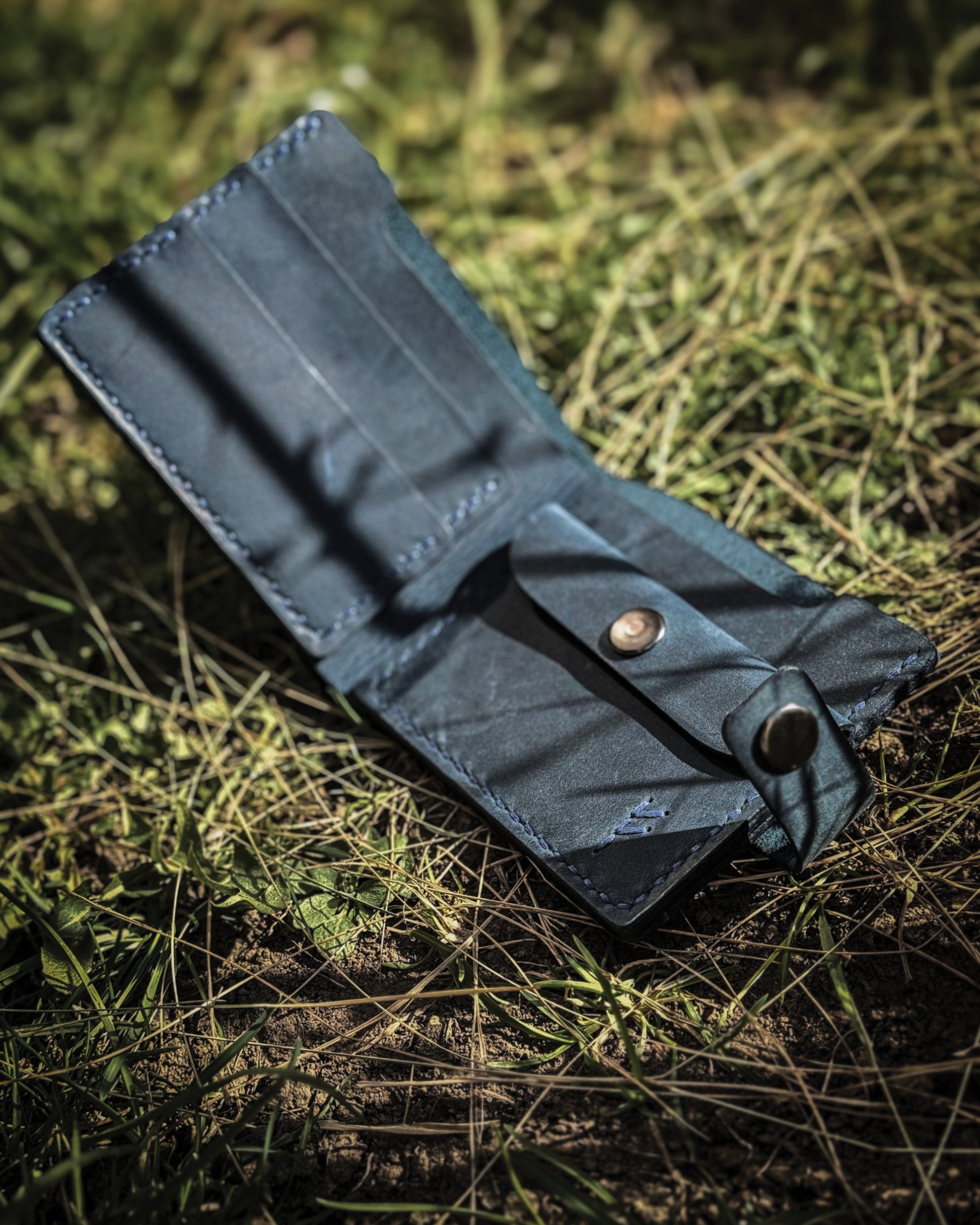 Handmade Viking leather wallets engraved with a custom Bindrune for wealth, prosperity & luck. Features stitched Fehu rune. Available in navy, black & green. Norse mythology meets everyday style.