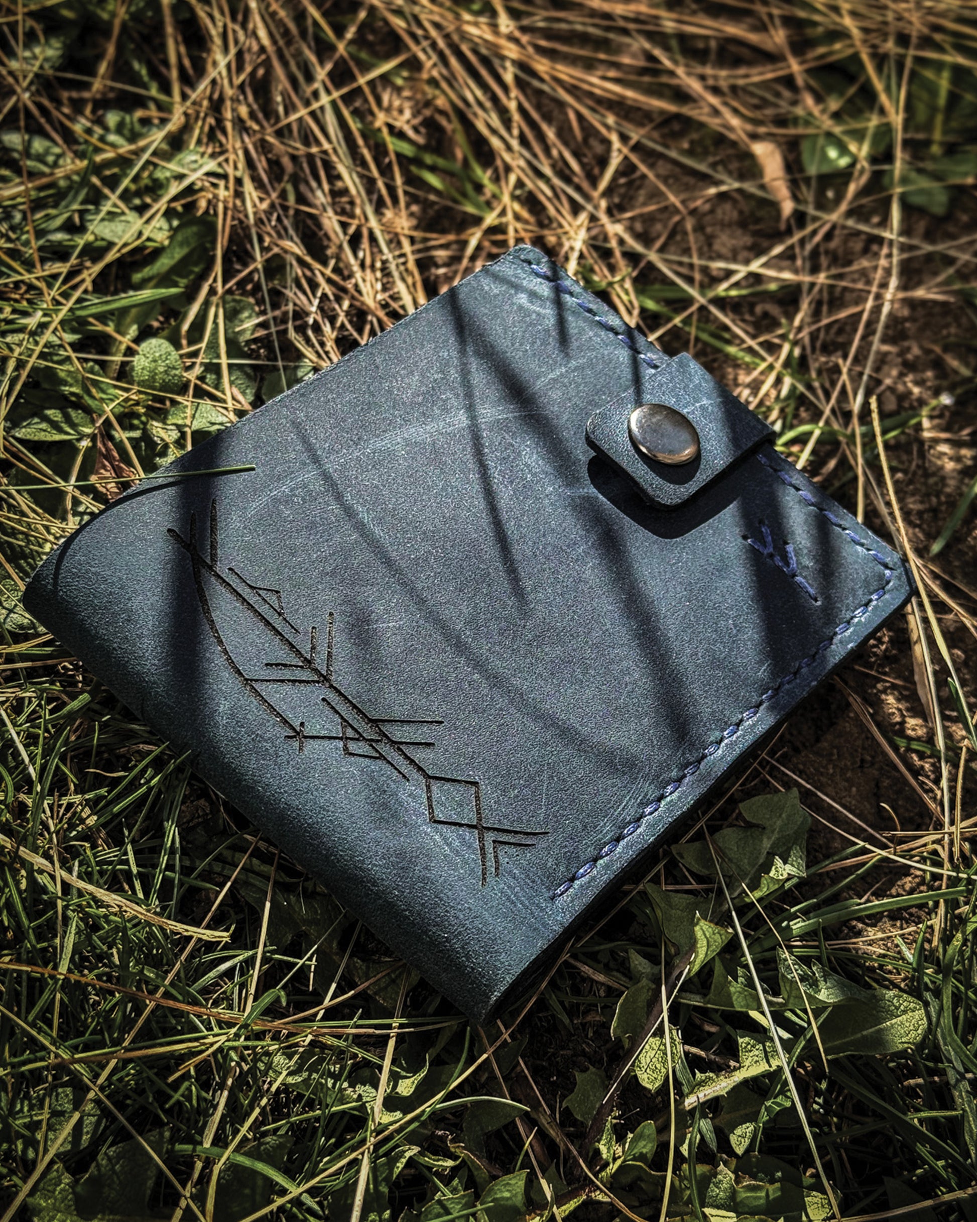 Handmade Viking leather wallets engraved with a custom Bindrune for wealth, prosperity & luck. Features stitched Fehu rune. Available in navy, black & green. Norse mythology meets everyday style.
