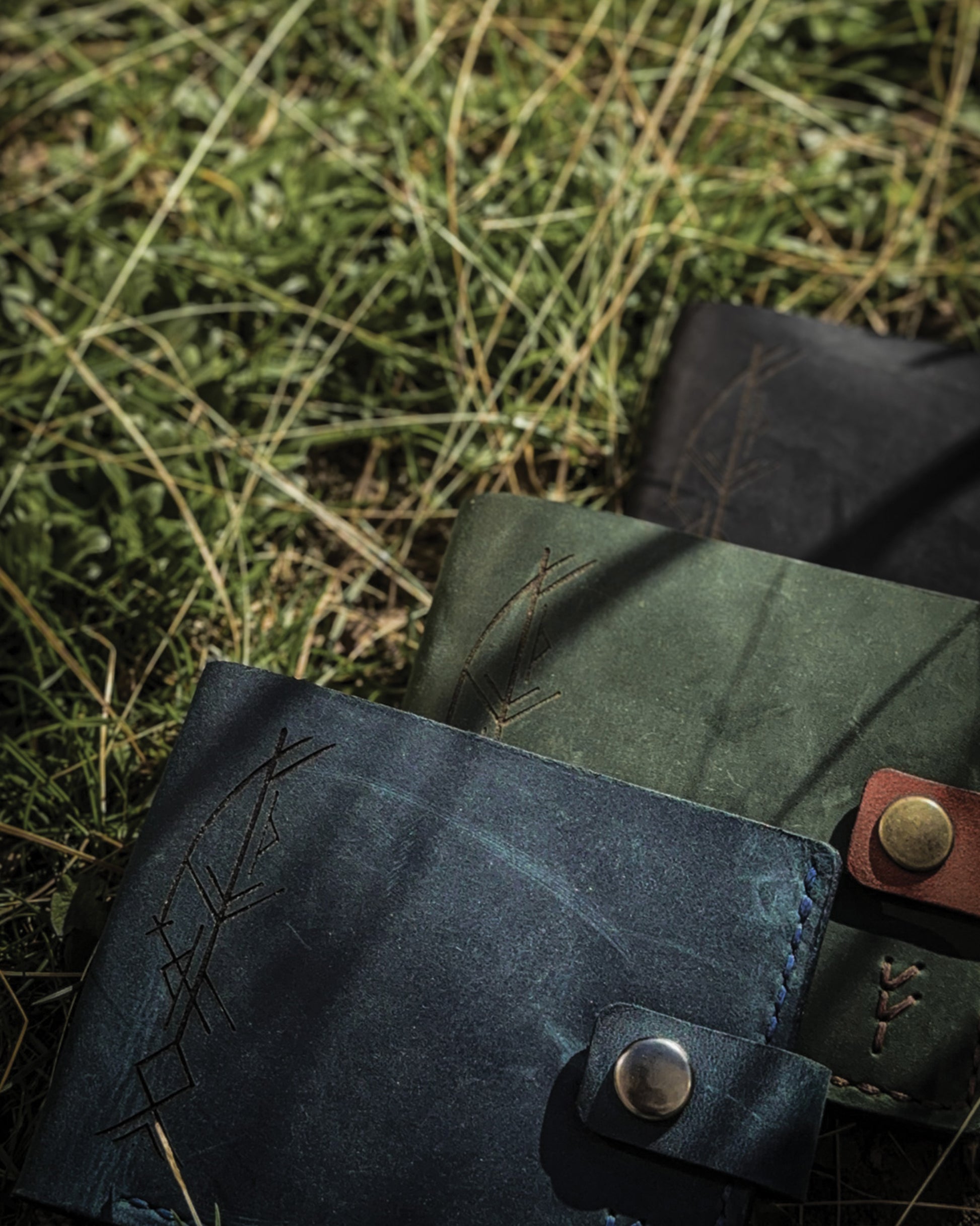 Handmade Viking leather wallets engraved with a custom Bindrune for wealth, prosperity & luck. Features stitched Fehu rune. Available in navy, black & green. Norse mythology meets everyday style.