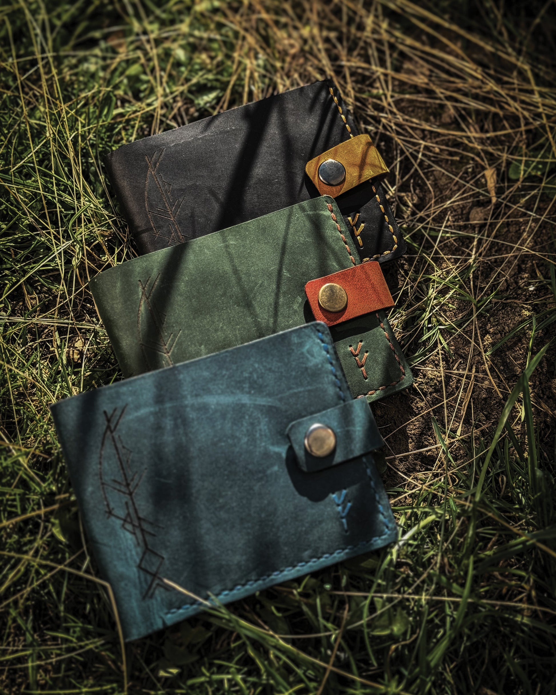 Handmade Viking leather wallets engraved with a custom Bindrune for wealth, prosperity & luck. Features stitched Fehu rune. Available in navy, black & green. Norse mythology meets everyday style.